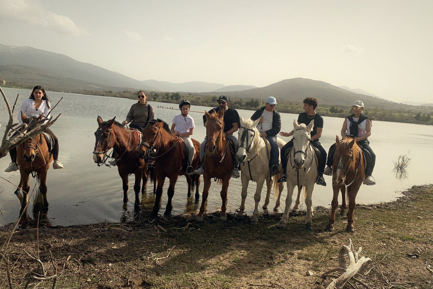 A family on horseback by a mountain lake