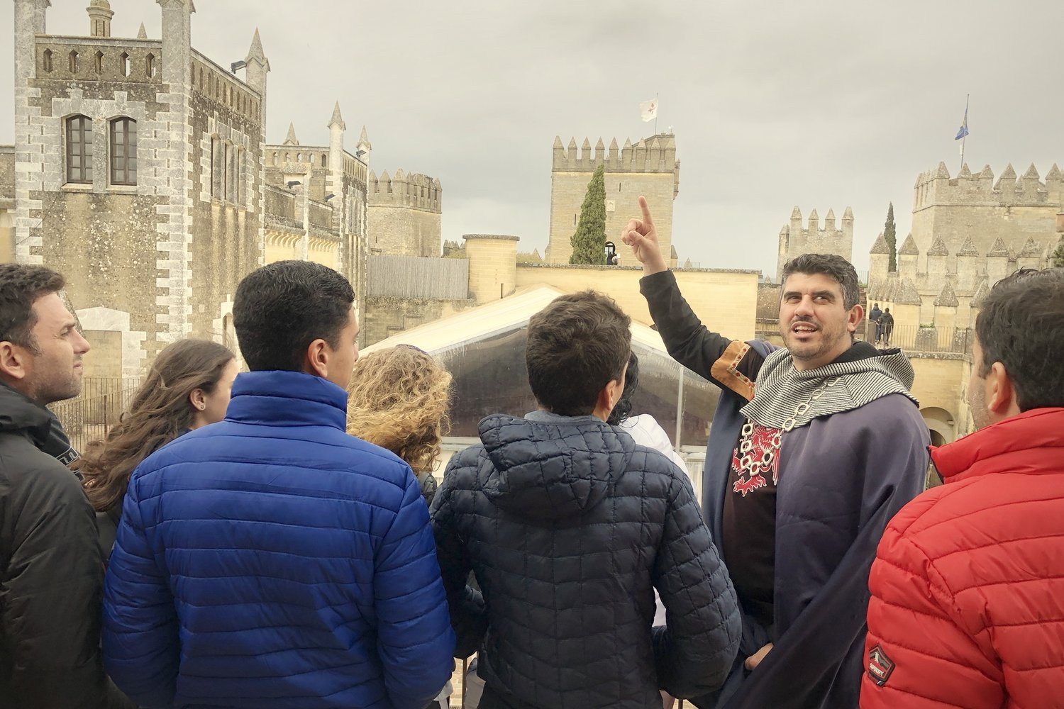 A guide in medieval costume pointing out the towers to a group