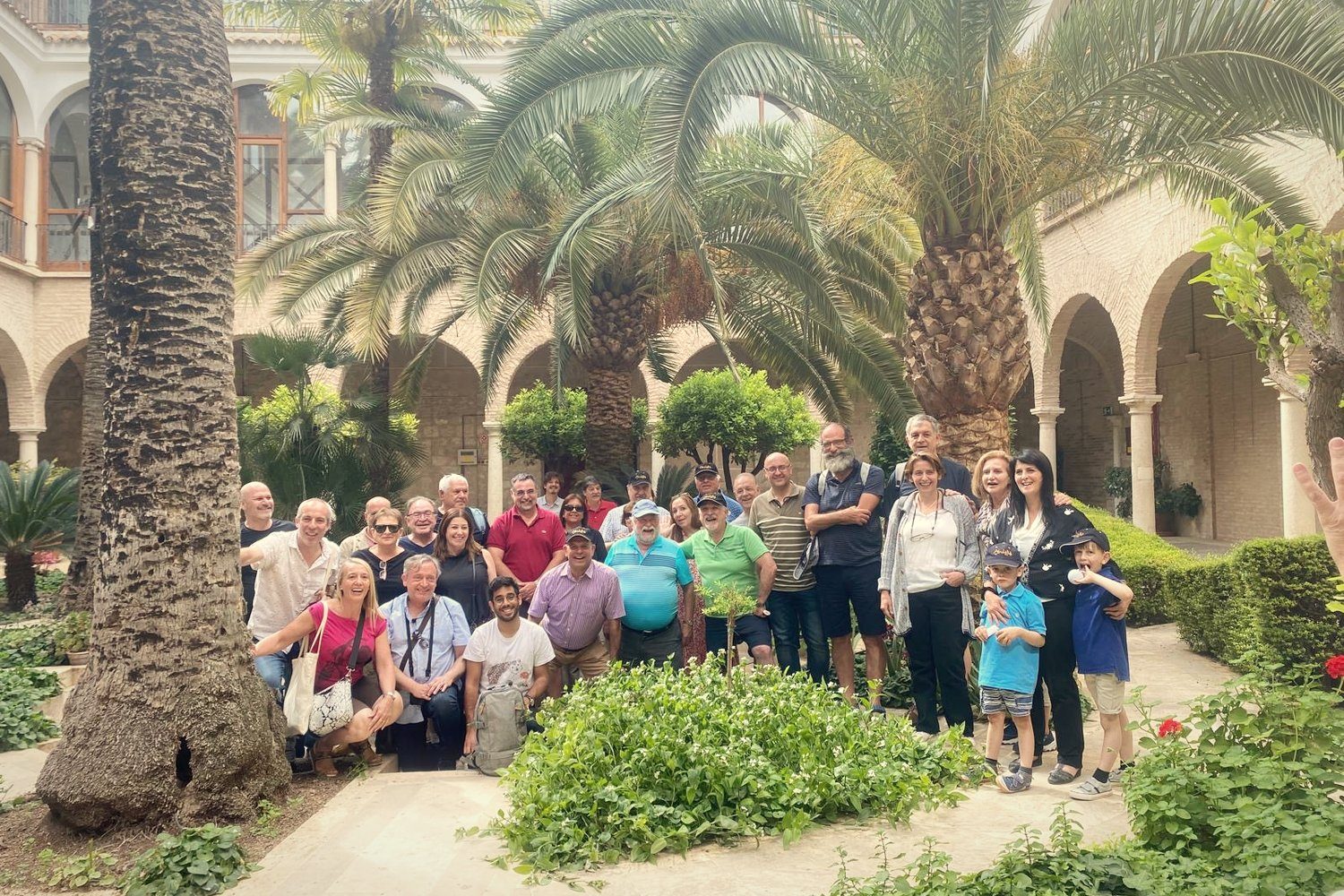 A large family group in a cloister garden with palm trees
